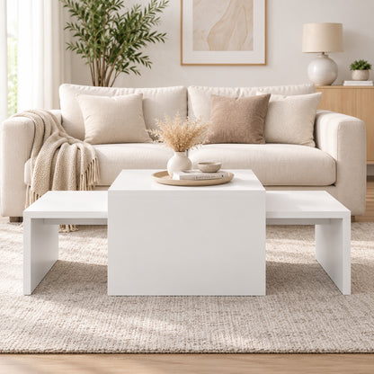 Table basse blanche design avec éléments gigognes, vue de face dans un salon moderne et lumineux.