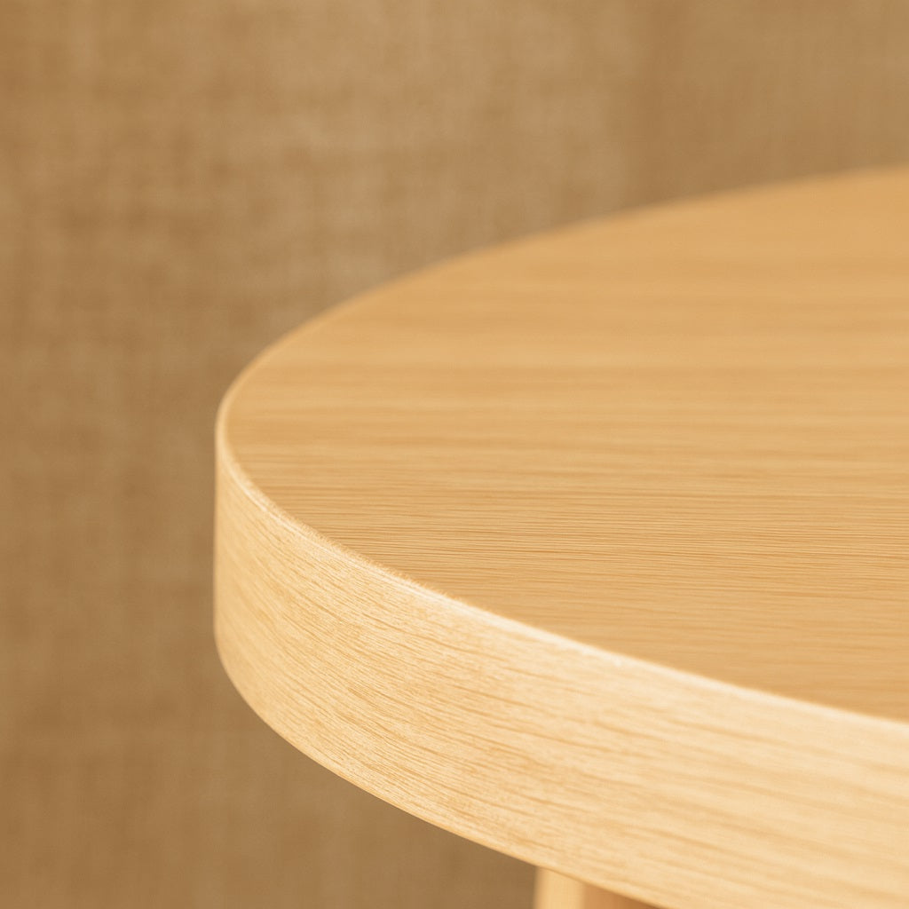Gros plan sur le plateau d’une table basse ronde en bois clair, finition naturelle et douce pour une table basse en bois haut de gamme.
