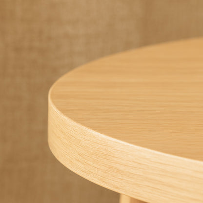 Gros plan sur le plateau d’une table basse ronde en bois clair, finition naturelle et douce pour une table basse en bois haut de gamme.