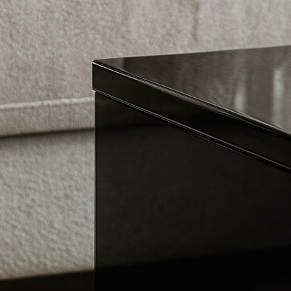Détail du plateau brillant d’une table basse relevable noire, finition laquée haut de gamme.