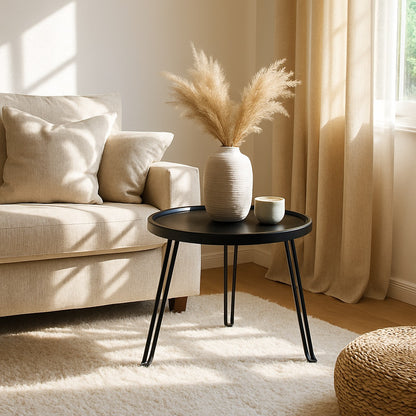 Table basse ronde noire Arcus dans un salon lumineux, style moderne et chaleureux.