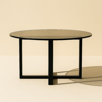 Table basse ronde en verre teinté et piètement noir croisé au style contemporain.