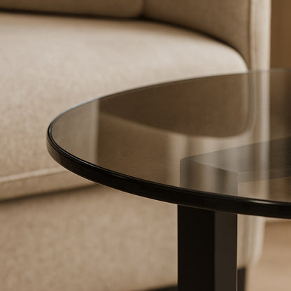 Détail du plateau de table basse ronde en verre fumé dans salon contemporain.