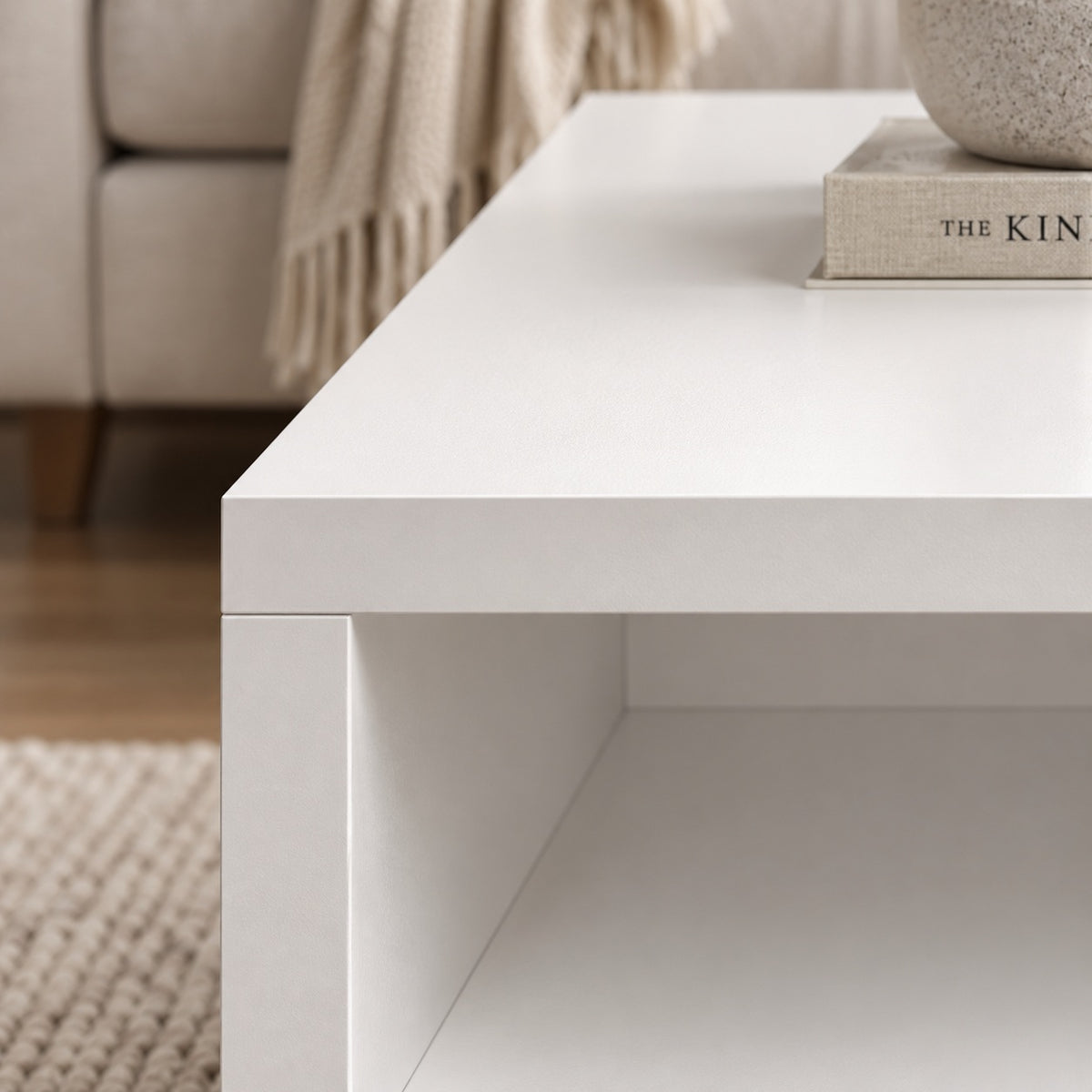Table basse blanche design en gros plan, finition épurée et niche de rangement dans un salon moderne.
