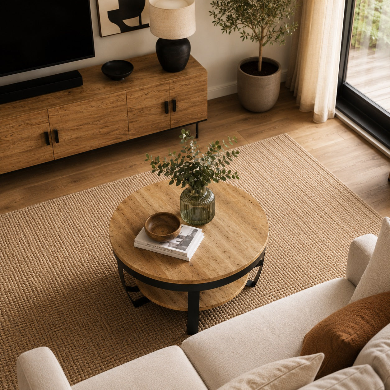 Vue plongeante sur table basse ronde en bois avec vase décoratif dans salon moderne et tapis texturé beige