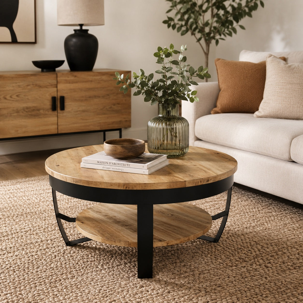 Table basse ronde en bois et métal noir dans salon chaleureux avec canapé beige et décoration naturelle