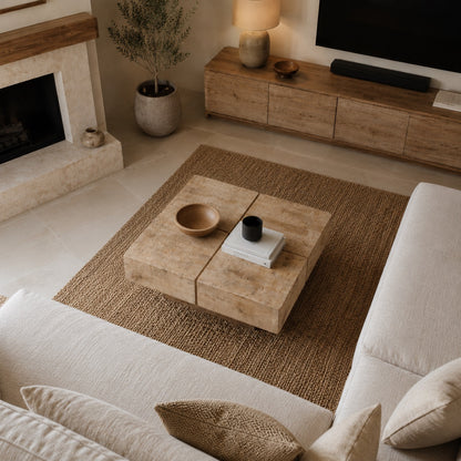 Vue plongeante à 60° sur table basse en bois naturel, salon moderne beige avec tapis texturé et lumière douce.