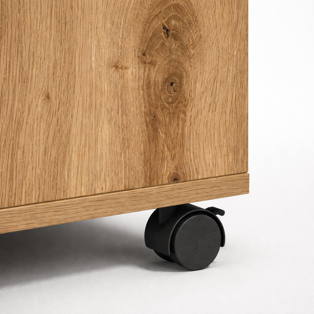 Détail de table basse en bois montrant la finition chêne et les roulettes, table basse de salon pratique.
