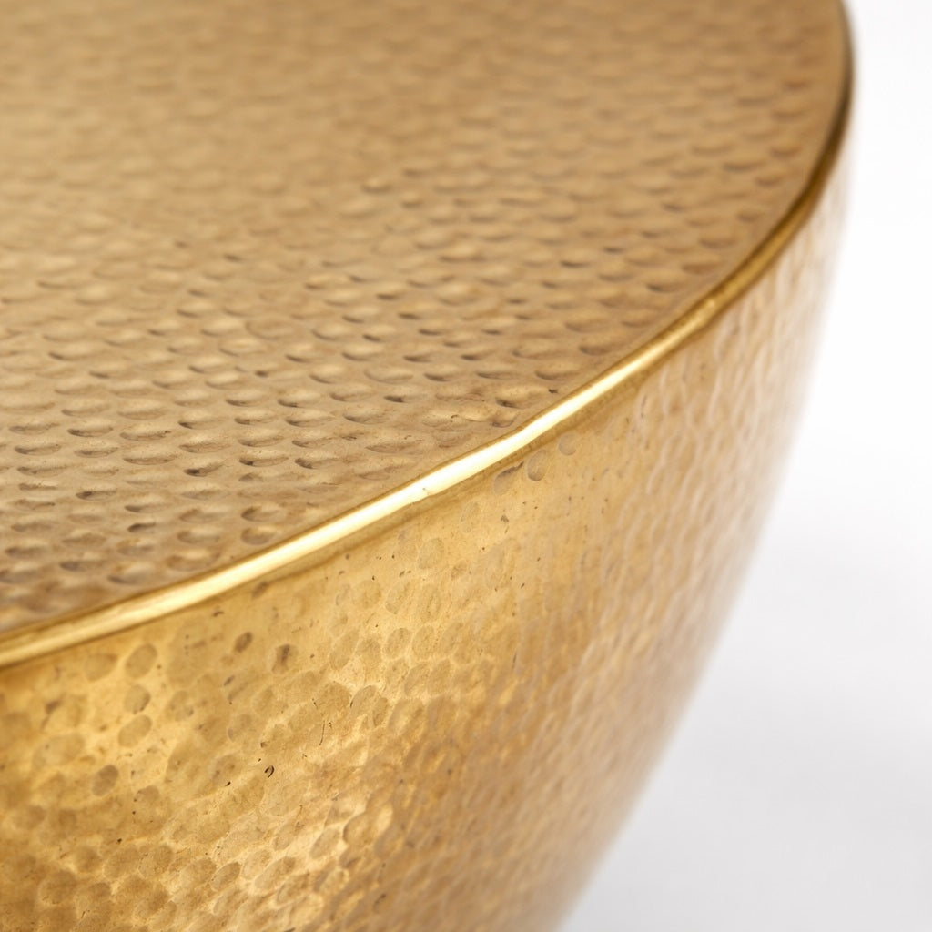Détail de table basse design ronde en métal doré martelé, texture artisanale haut de gamme.