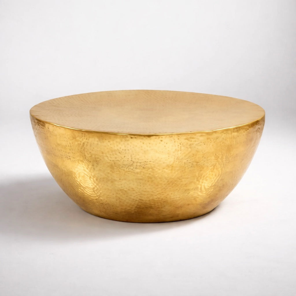 Table basse ronde design en métal doré, finition martelée artisanale, photo studio fond blanc.