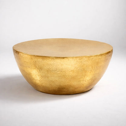 Table basse ronde design en métal doré, finition martelée artisanale, photo studio fond blanc.