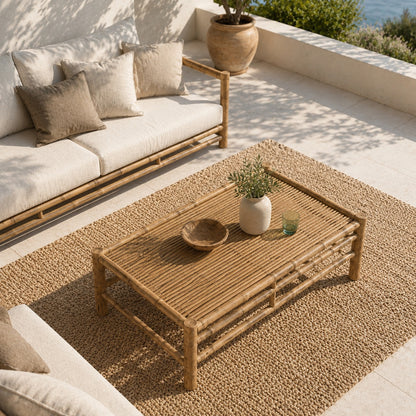 Table basse de jardin en bambou vue à 60° en plongée, sur terrasse méditerranéenne avec mobilier beige et vue sur la mer.
