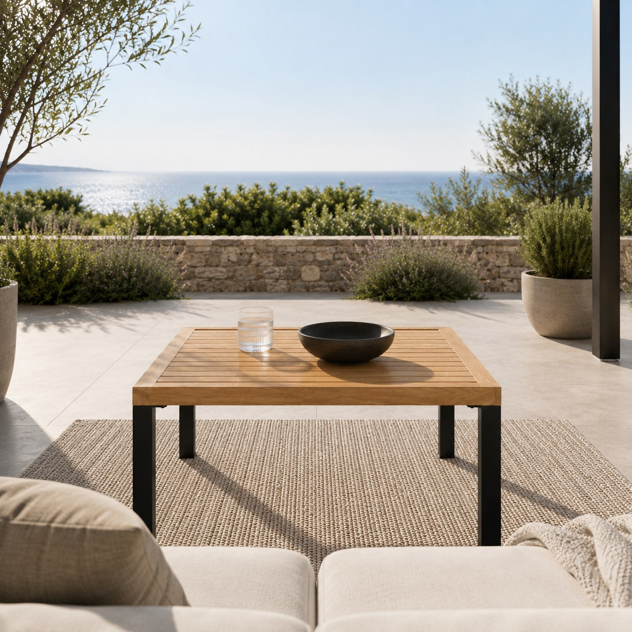 Table basse de jardin en bois et métal noir sur terrasse avec vue mer, idéale pour un salon d’extérieure