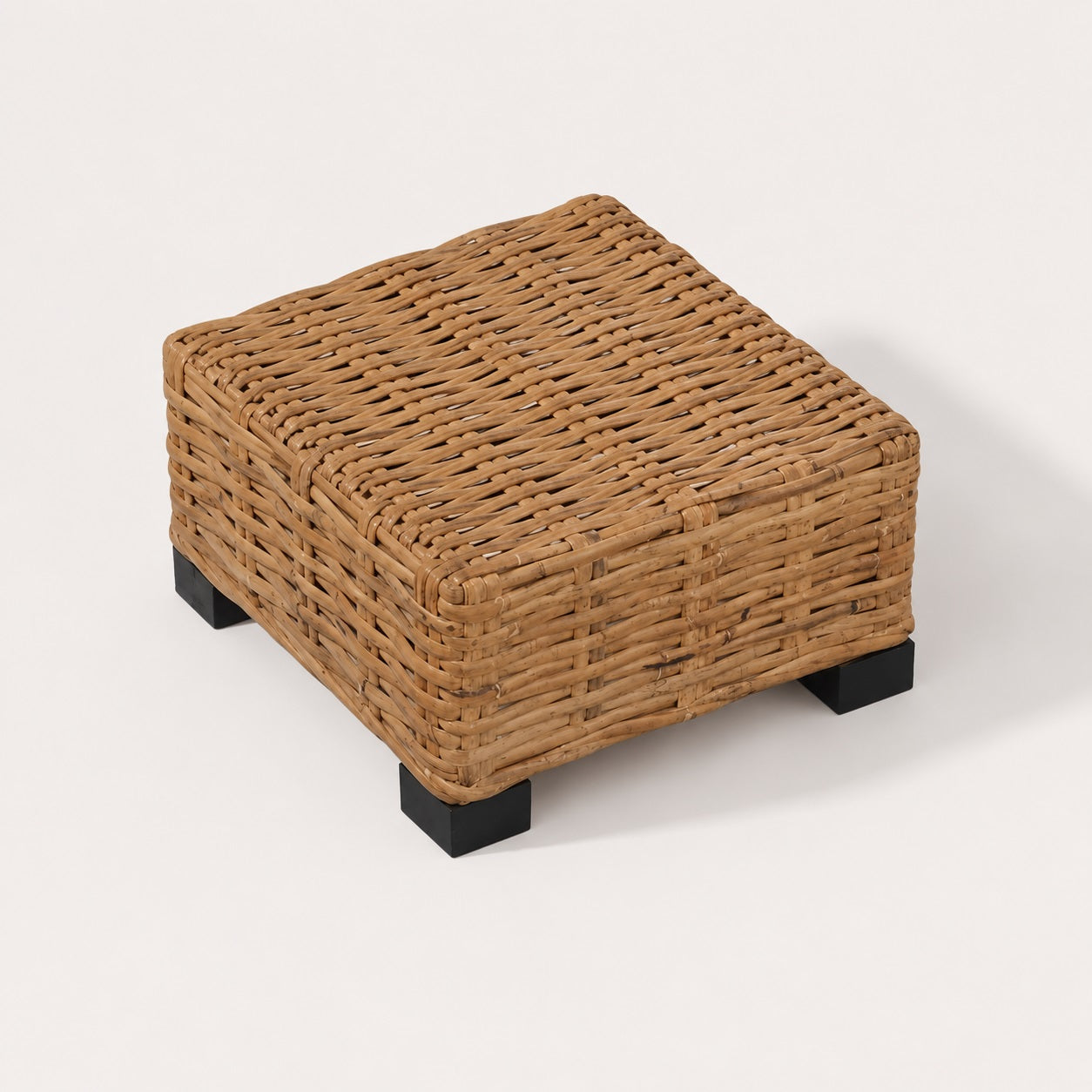Vue haute d’une table basse de jardin en rotin tressé avec pieds noirs, table basse d’extérieur compacte design naturel.