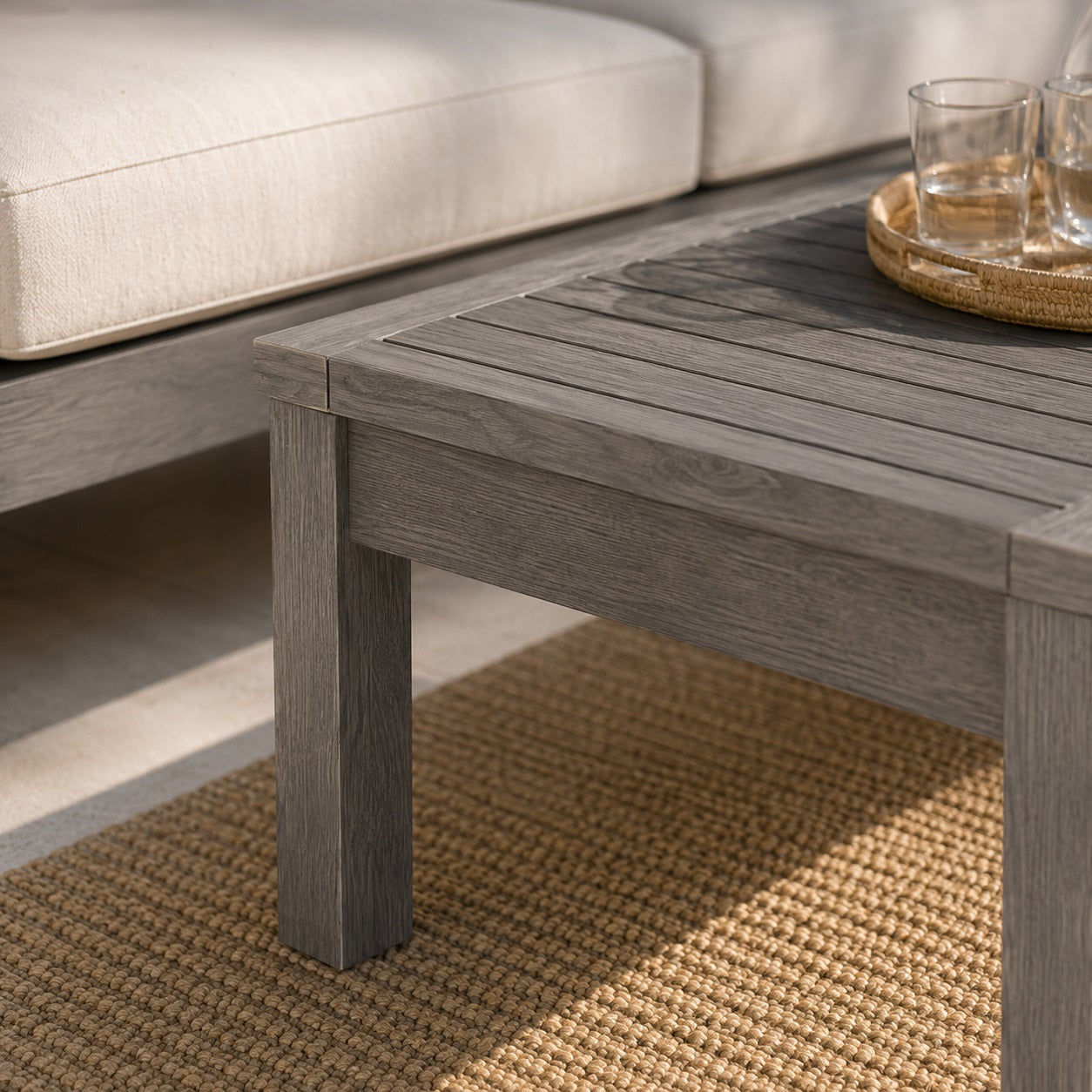 Gros plan sur une table basse de jardin en bois gris, mettant en valeur la texture naturelle du bois.