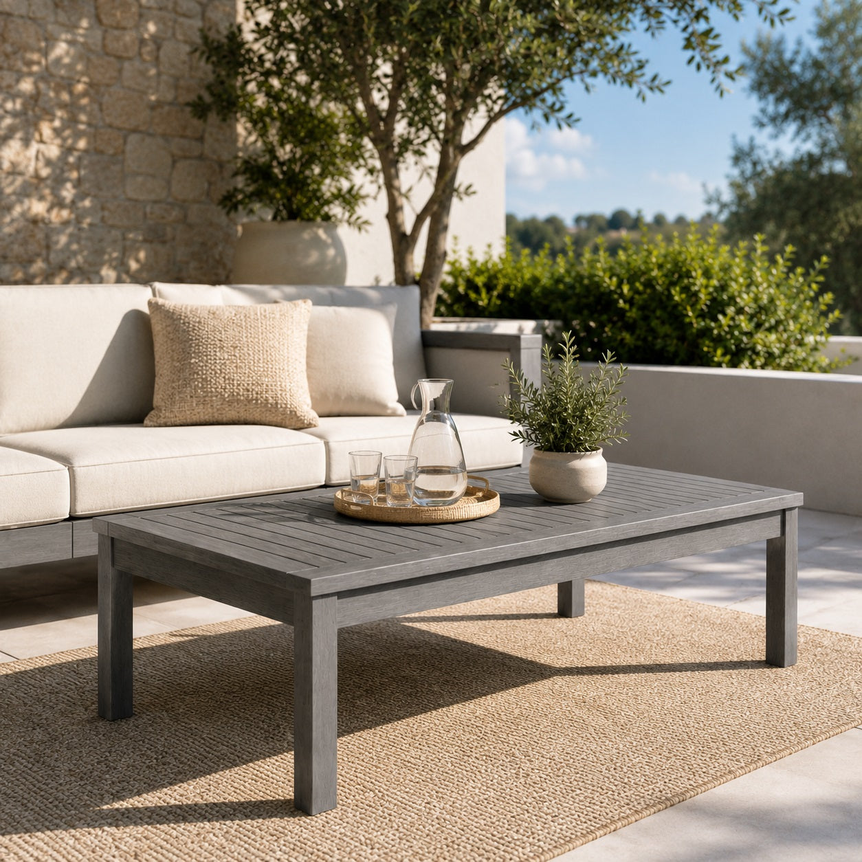 Table basse d’extérieur grise sur terrasse moderne avec canapé lounge et décoration naturelle