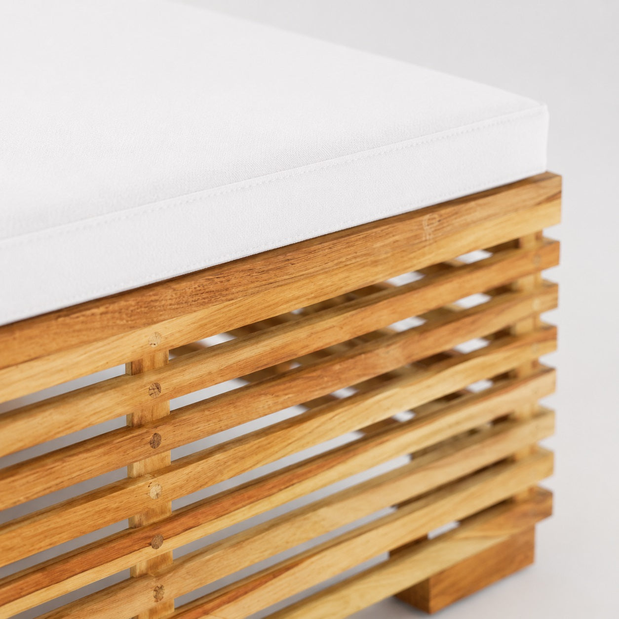 Zoom sur coussin blanc et bois massif, table basse de jardin et mobilier d’extérieure haut de gamme