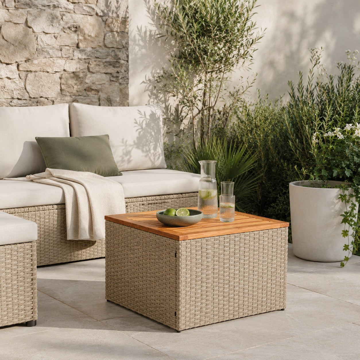 Table basse de jardin beige en résine tressée et bois naturel dans un salon d’extérieure élégant et cosy.