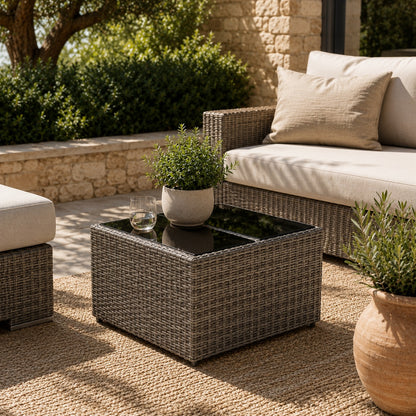 Table basse de jardin grise en résine tressée dans un salon d’extérieure moderne et chaleureux.