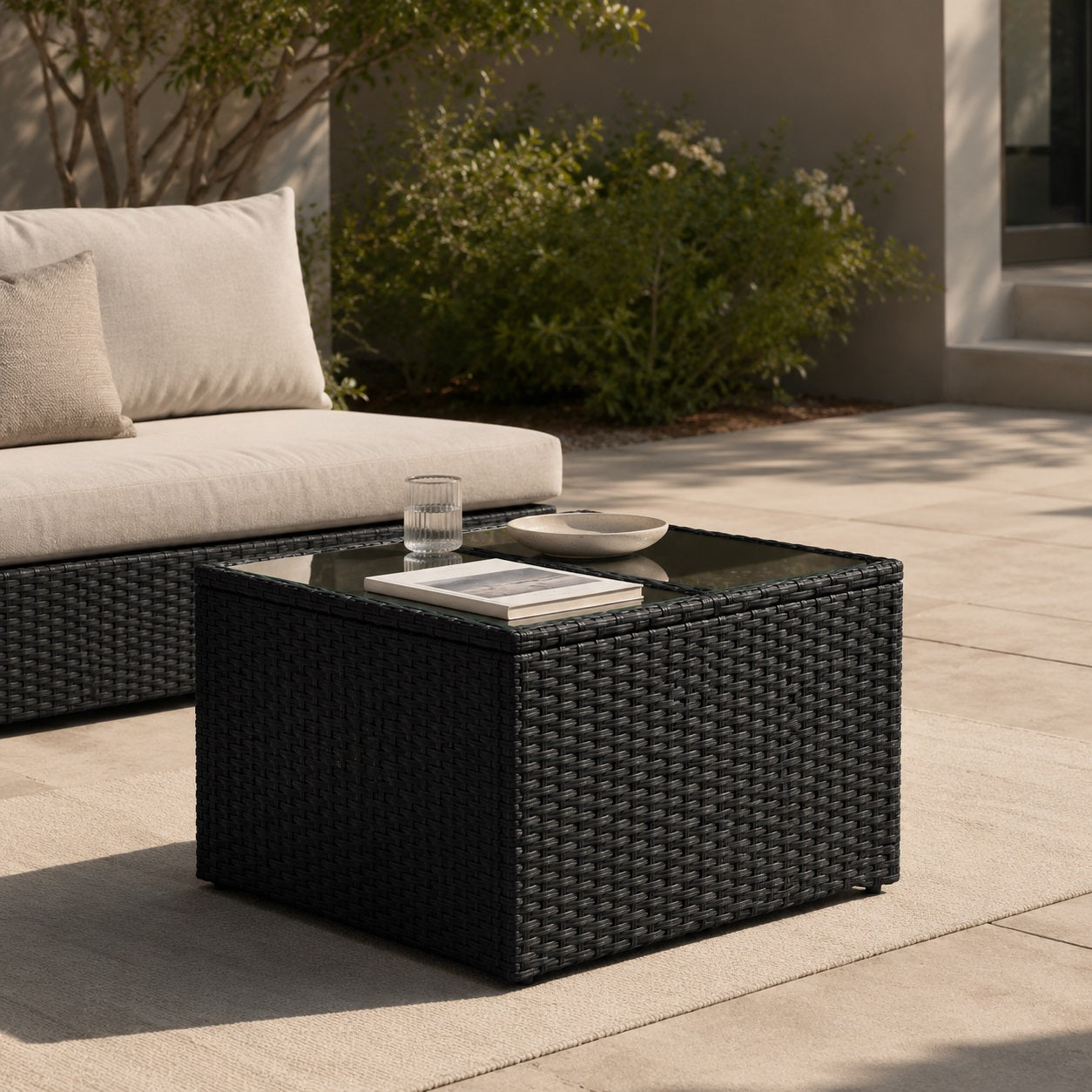Table basse de jardin noire avec plateau en verre dans un salon d’extérieure élégant et moderne.