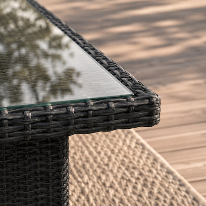 Gros plan d'une table basse de jardin en résine tressée noire avec plateau en verre trempé transparent, finition haut de gamme.
