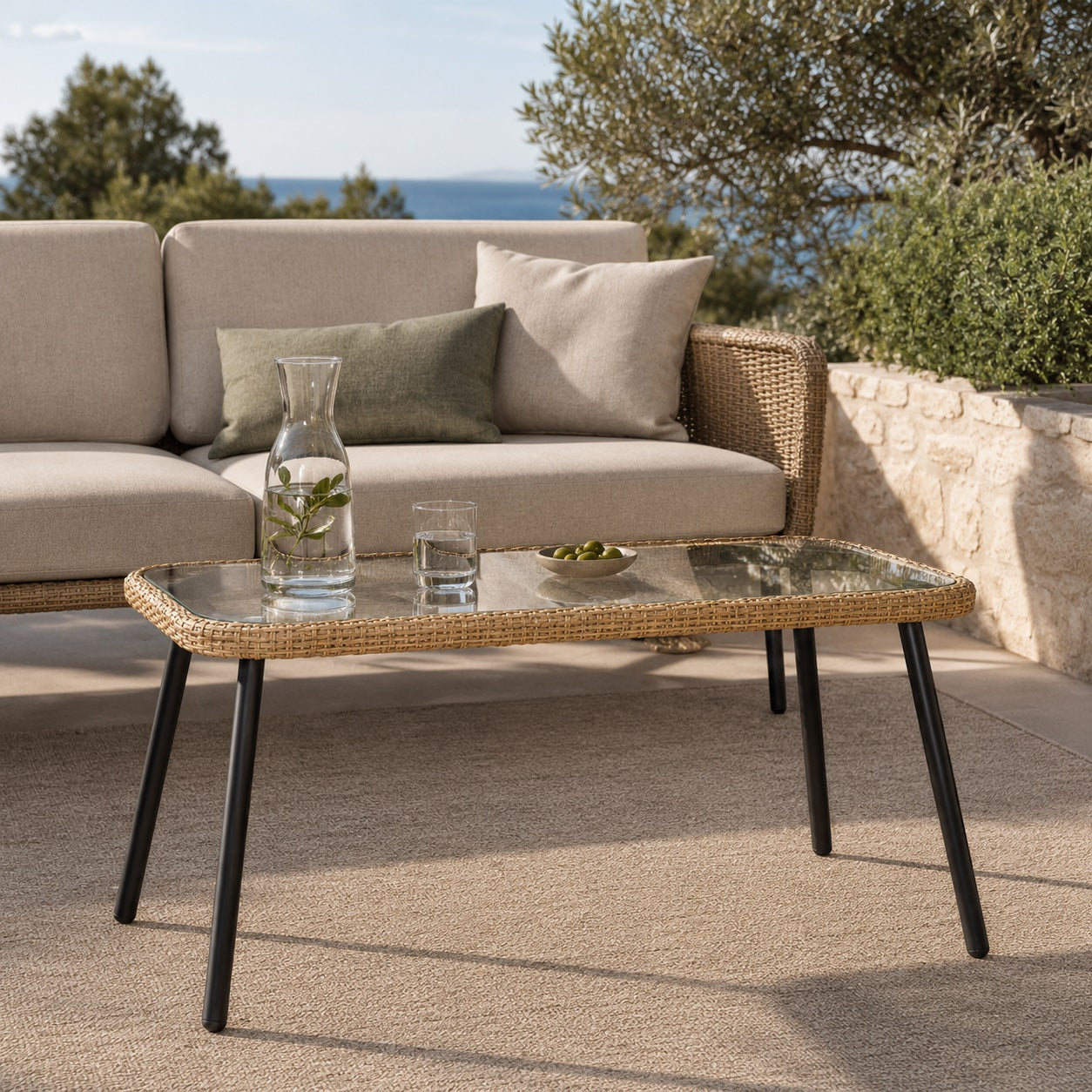 Table basse d’extérieur Nevara beige en verre et résine tressée sur terrasse contemporaine.