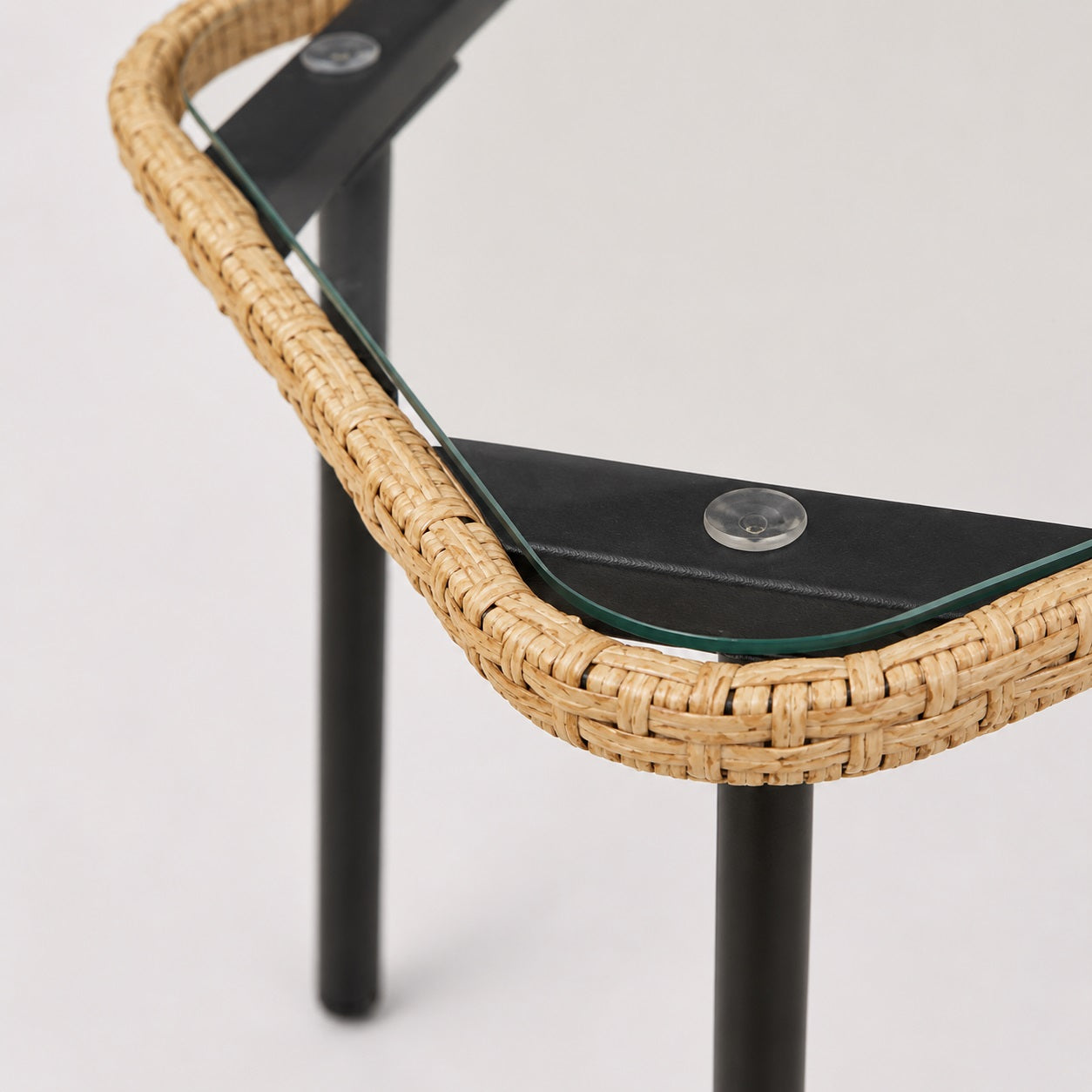 Détail de la table basse d’extérieur Nevara beige en résine tressée et plateau en verre.