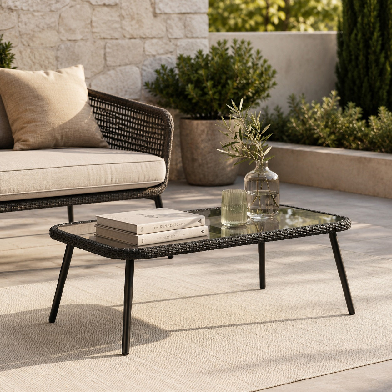 Table basse d’extérieur Nevara noire sur terrasse moderne avec décoration naturelle.