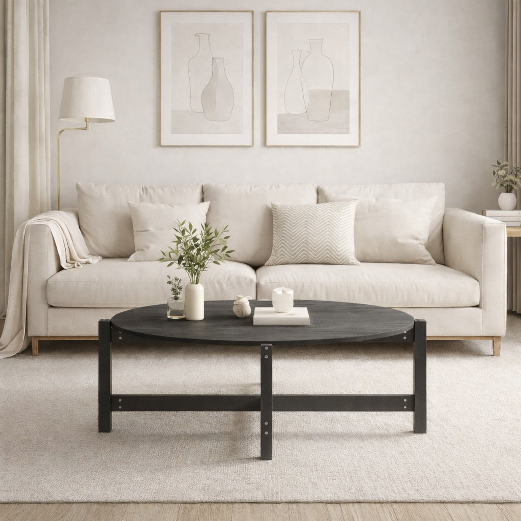 Table basse grise de salon au design rond, présentée dans un intérieur moderne avec canapé clair et décoration épurée.