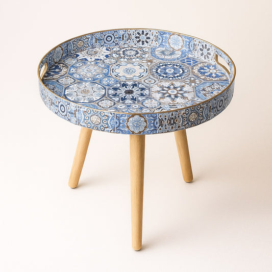 Table basse ronde de salon avec plateau motif azulejos bleus et pieds en bois clair.