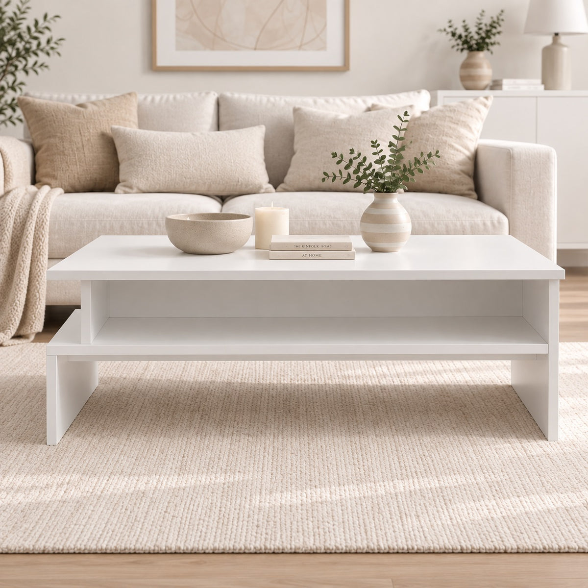 Table basse de salon blanche avec étagère de rangement, vue de face dans un intérieur moderne aux tons naturels.