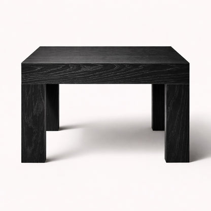 Table basse noire de salon au design structuré, plateau épais et piètement massif pour un intérieur moderne.